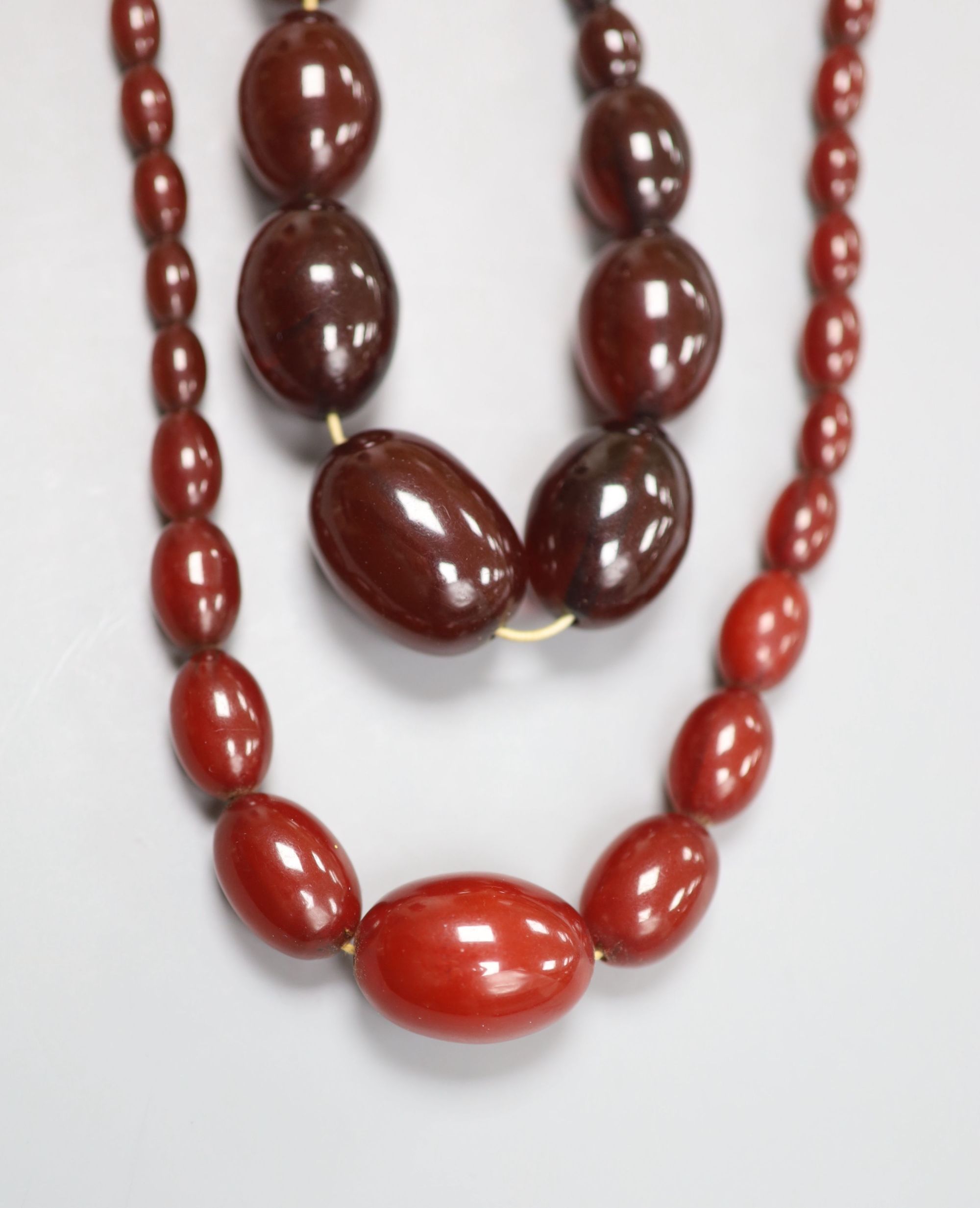 Two single strand graduated simulated cherry amber bead necklaces, 34cm & 58cm, gross 106 grams.